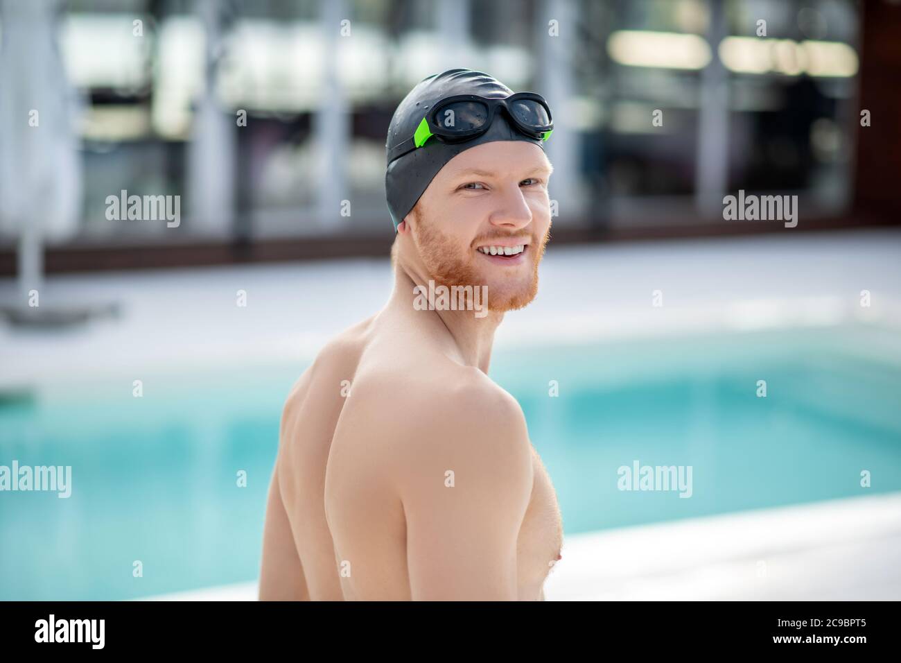 Hombre guapo con gorra de baño y gafas en la piscina