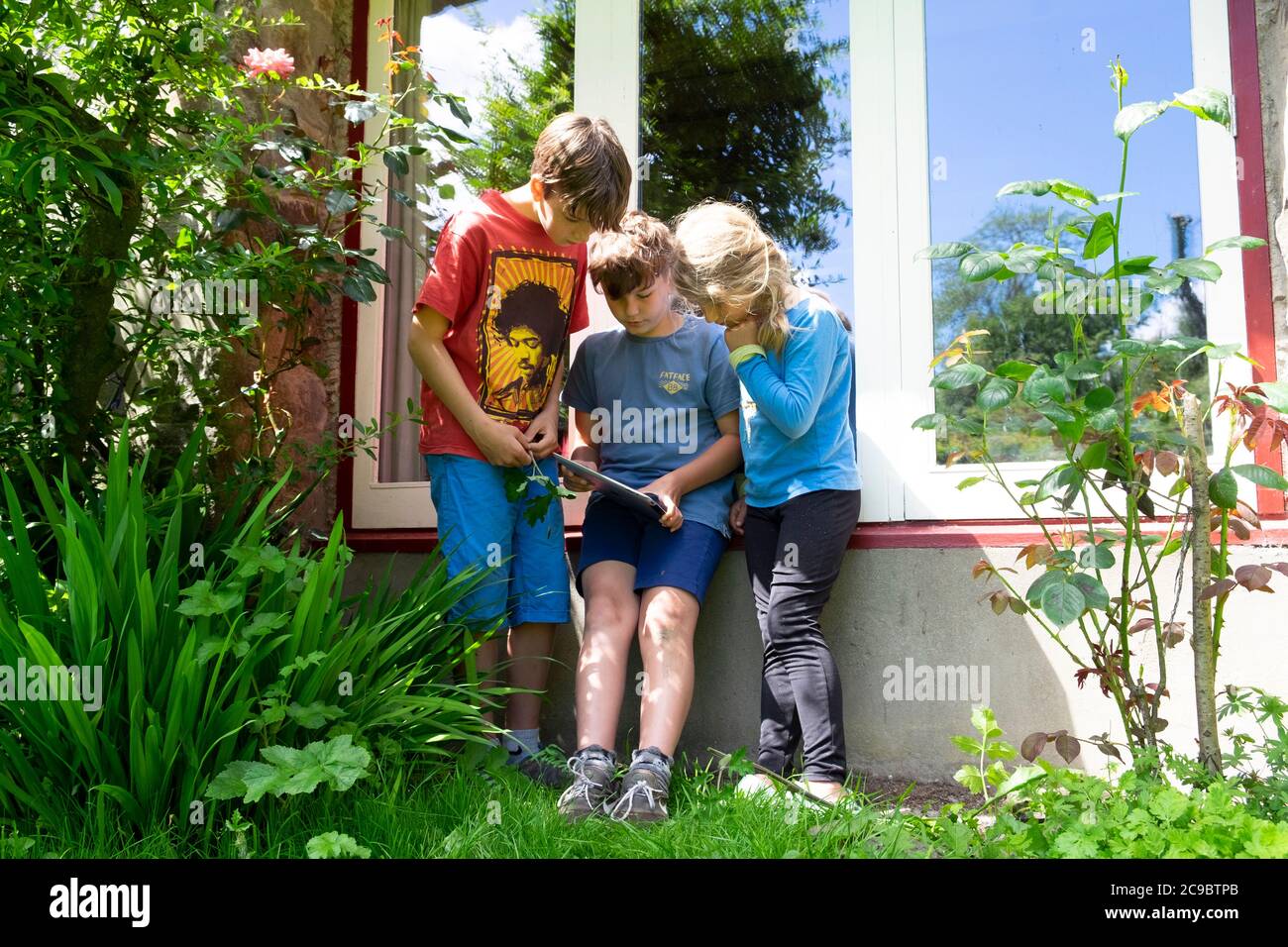 Niños niños niños amigos jugando a ipad en la estaycation en el campo después de Covid 19 cierre se ha aliviado Carmarthenshire Wales Reino Unido KATHY DEWITT Foto de stock