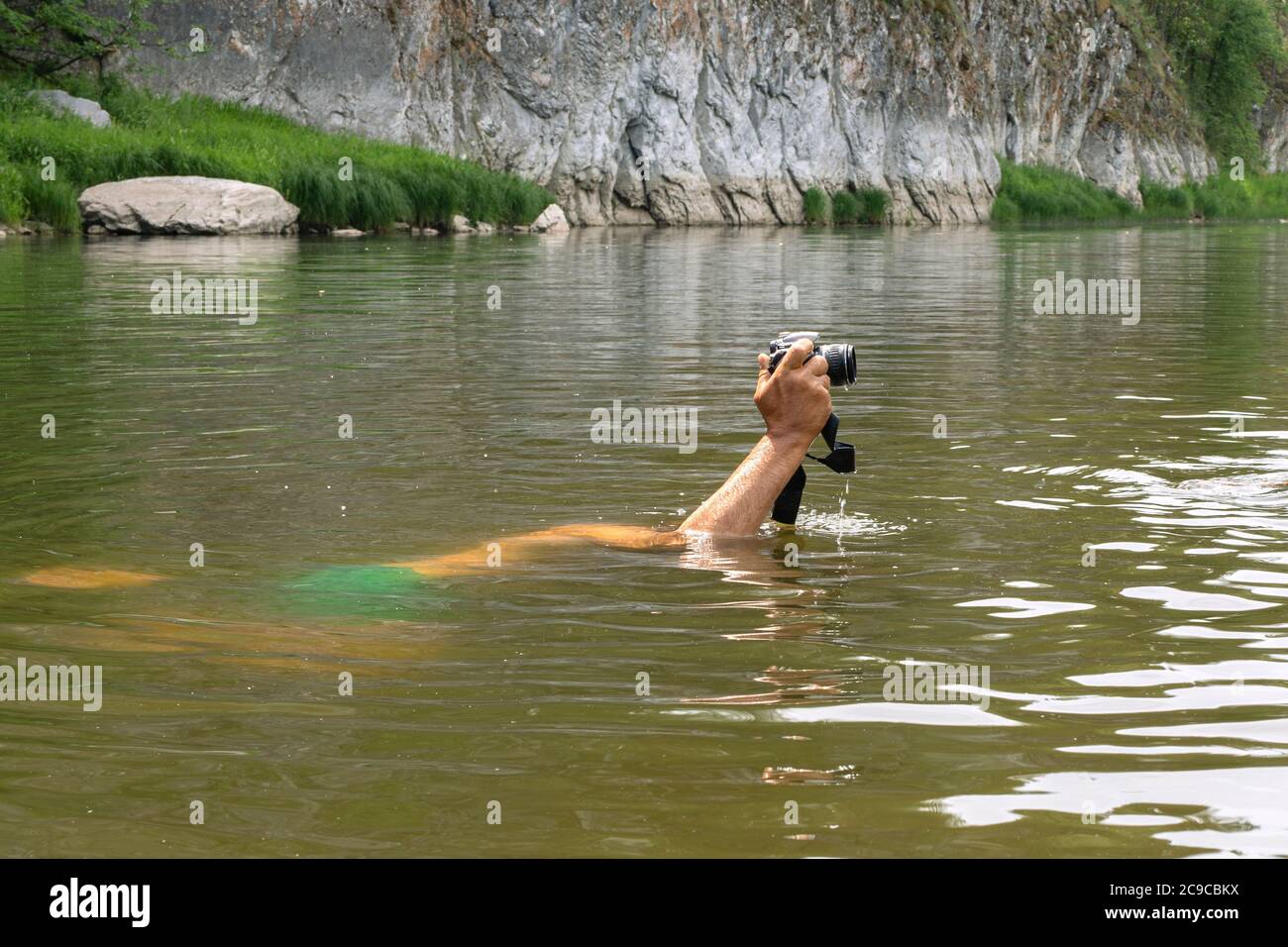 Hombre buceando bajo agua sosteniendo la cámara en mano sobre el Persona nadando en el depósito de agua natural haciendo fotos con la cámara digital. Naturaleza, salvaje Fotografía de