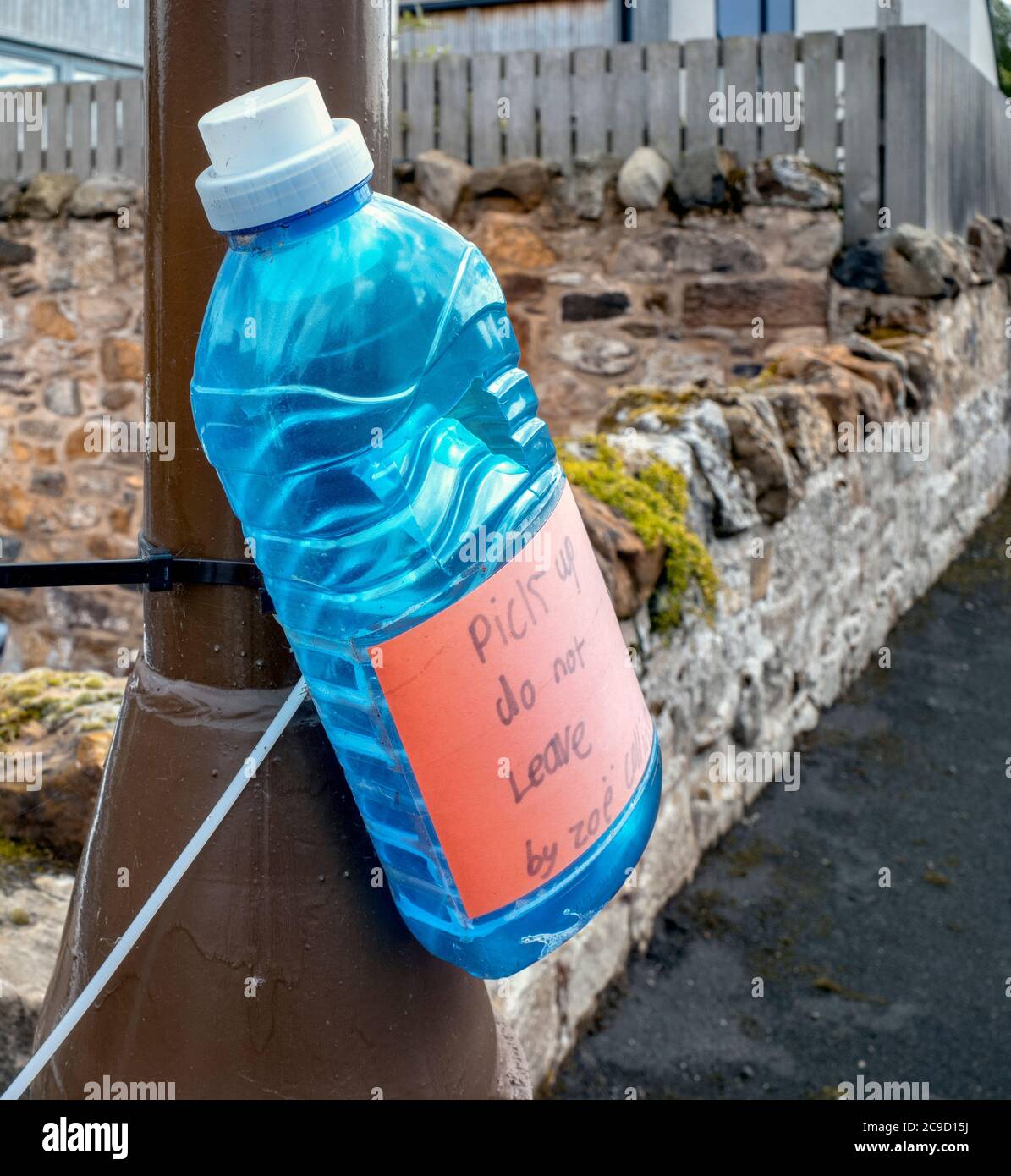 Nuevo aviso de basura de una botella de plástico descartada adherida a un poste de cordero. Foto de stock