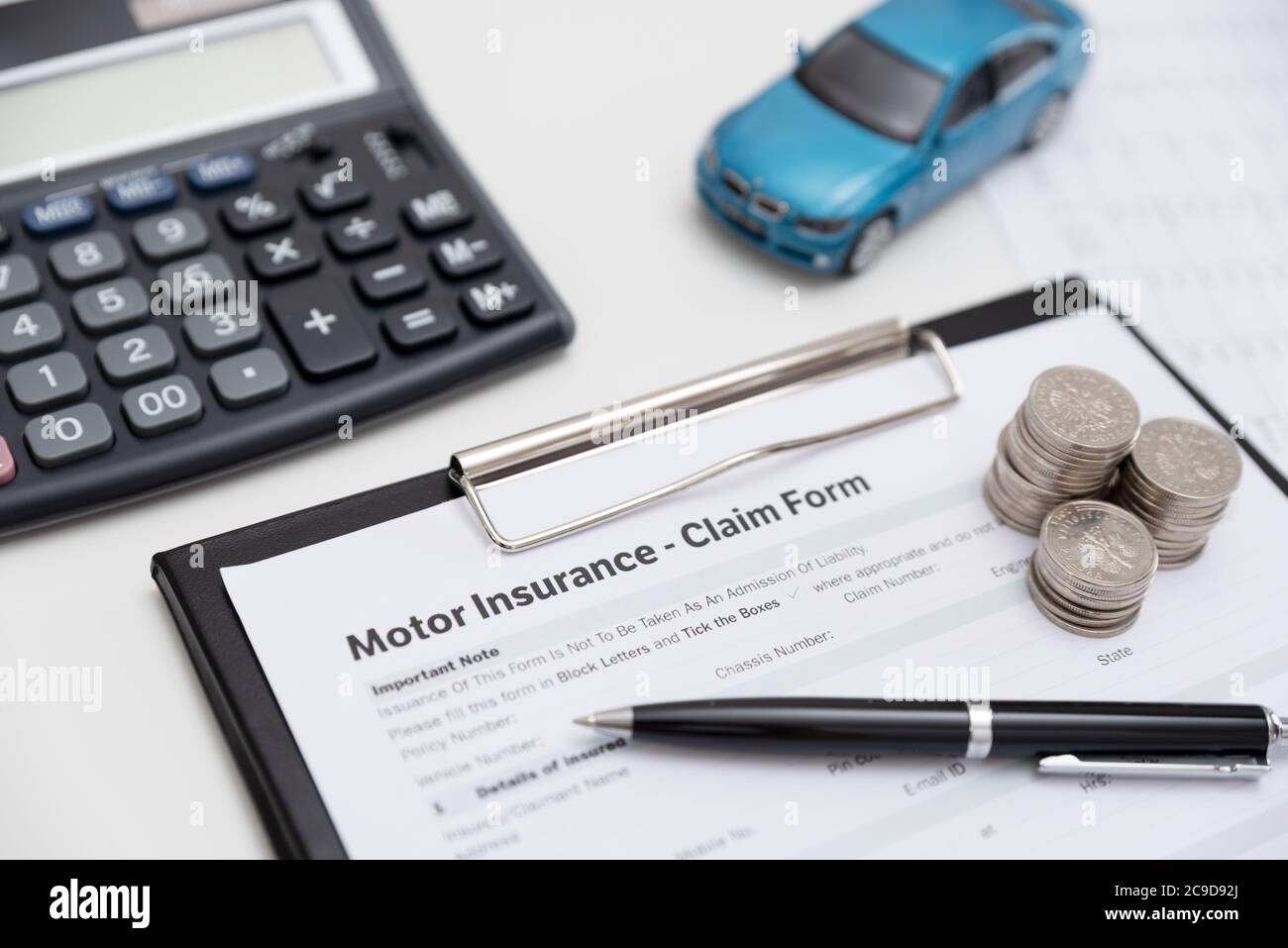 Motor o formulario de reclamación de seguros de coche con pila de monedas, calculadora y modelo de automóvil. Foto de stock