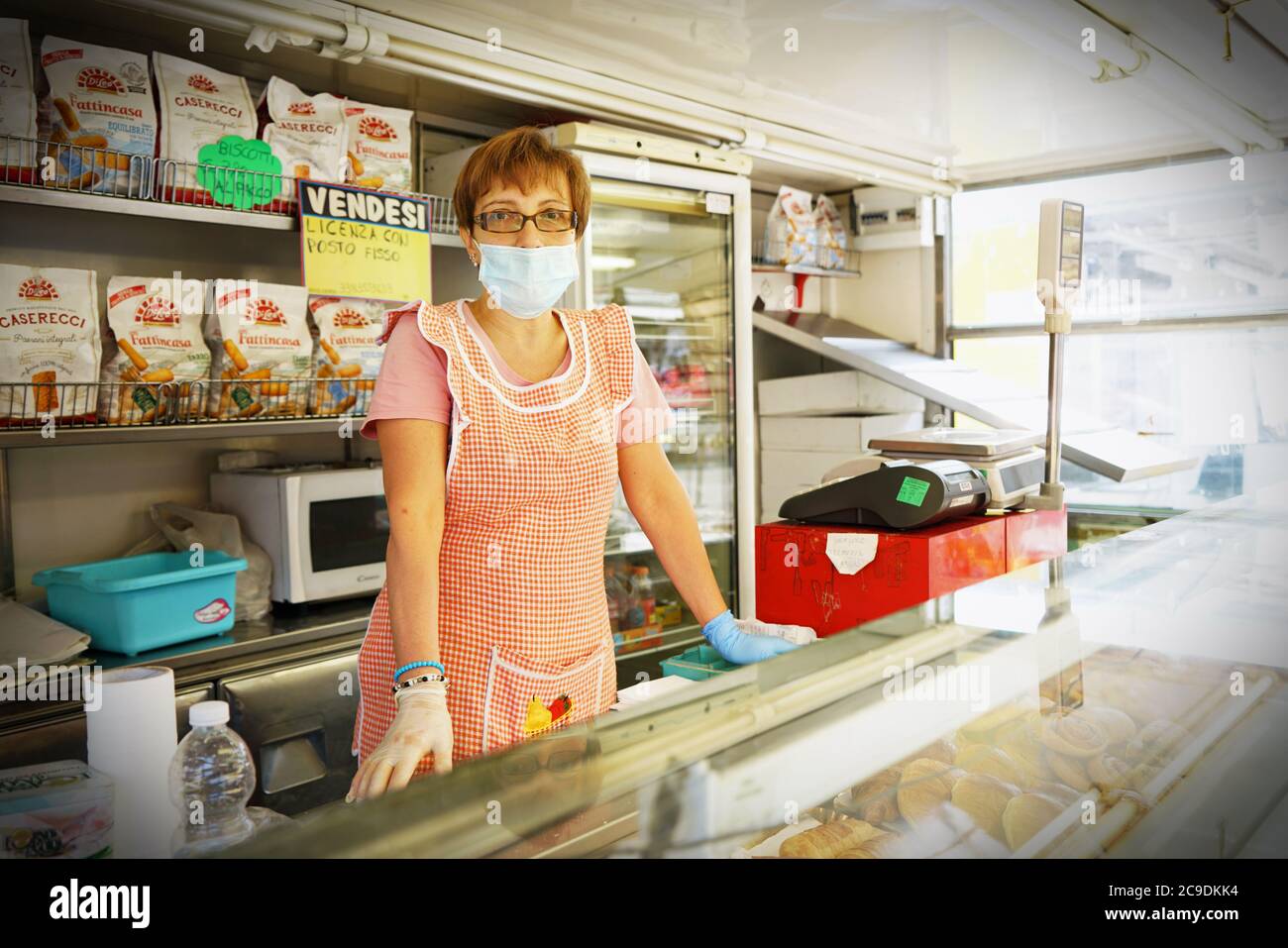 Un comerciante con una máscara covid-19, en el trabajo a pesar de la crisis económica debido al coronavirus . Turín, Italia - Mayo 2020 Foto de stock