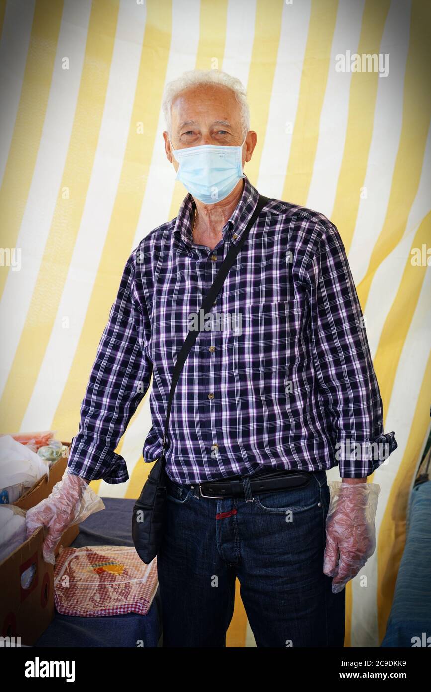 Un comerciante con una máscara covid-19, en el trabajo a pesar de la crisis económica debido al coronavirus . Turín, Italia - Mayo 2020 Foto de stock