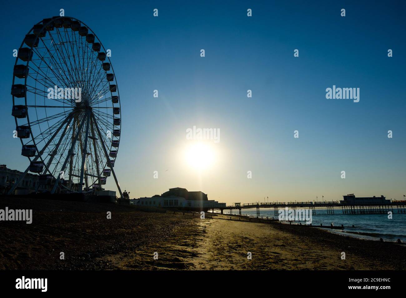 Worthing Beach, Worthing, Reino Unido. 31 de julio de 2020. El sol se eleva sobre el muelle y la rueda de observación en lo que se prevé que será uno de los días más calurosos del año. Imagen de crédito: Julie Edwards/Alamy Live News Foto de stock