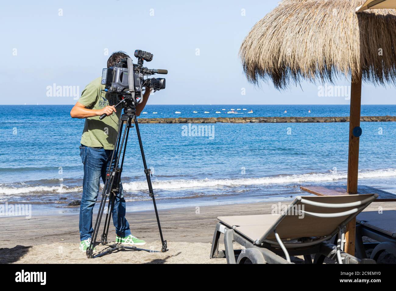 Costa Adeje, Tenerife, Islas Canarias, España. 24 de julio de 2020. TV  camarógrafo películas en Playa Fanabe playa para un informe sobre la isla  da la bienvenida a los turistas Fotografía de