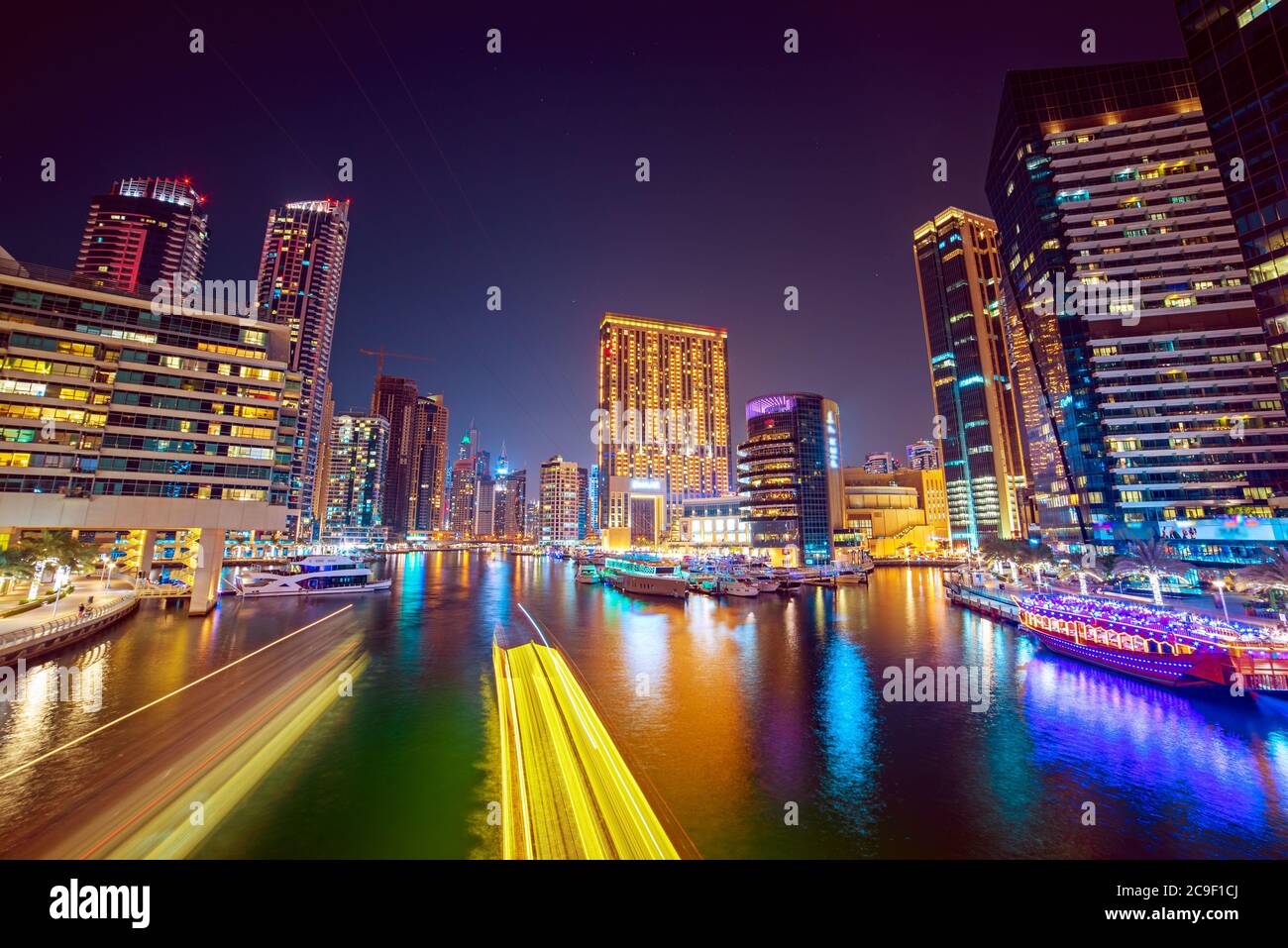 Dubai Marina por la noche con rascacielos, barcos y reflexiones en el agua, Emiratos Árabes Unidos Foto de stock