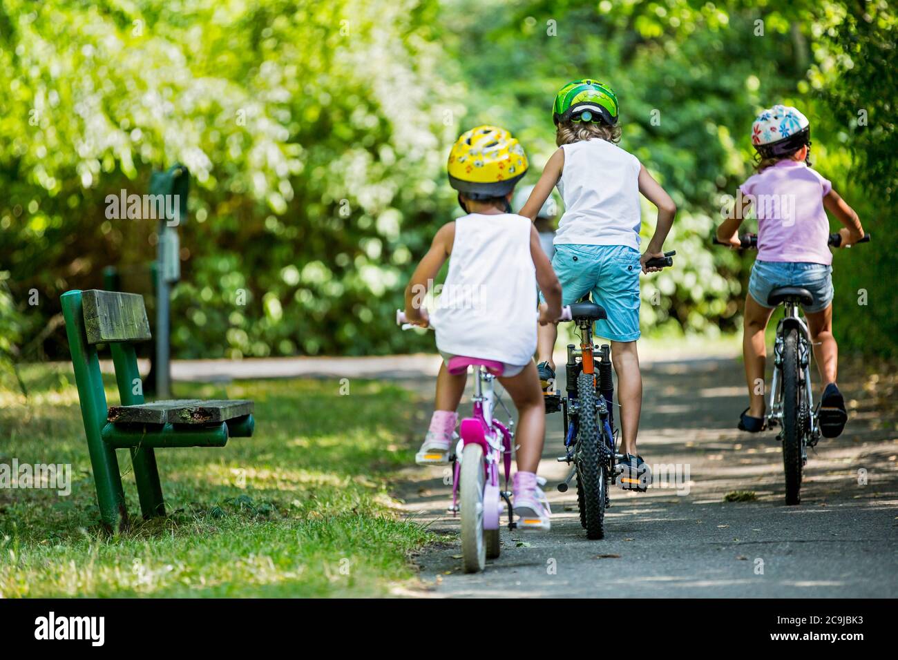 Niños que usan helmeta y ciclismo en el parque. Foto de stock