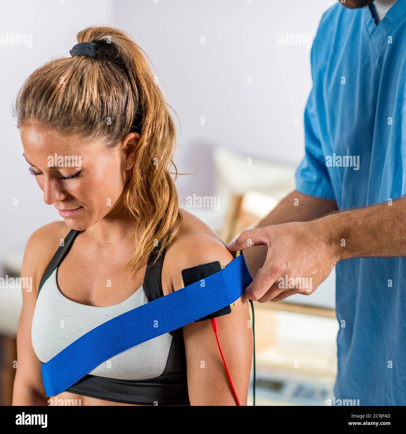 Estimulación muscular eléctrica en terapia física. El terapeuta coloca los  electrodos en el hombro del paciente Fotografía de stock - Alamy