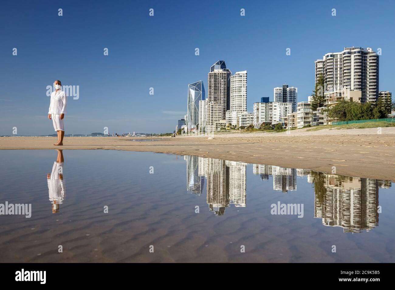 hombre con máscara médica caminando en la playa durante la pandemia del coronavirus covid 19, concepto de distancia social, ejercicio masculino usando máscara para la protección Foto de stock