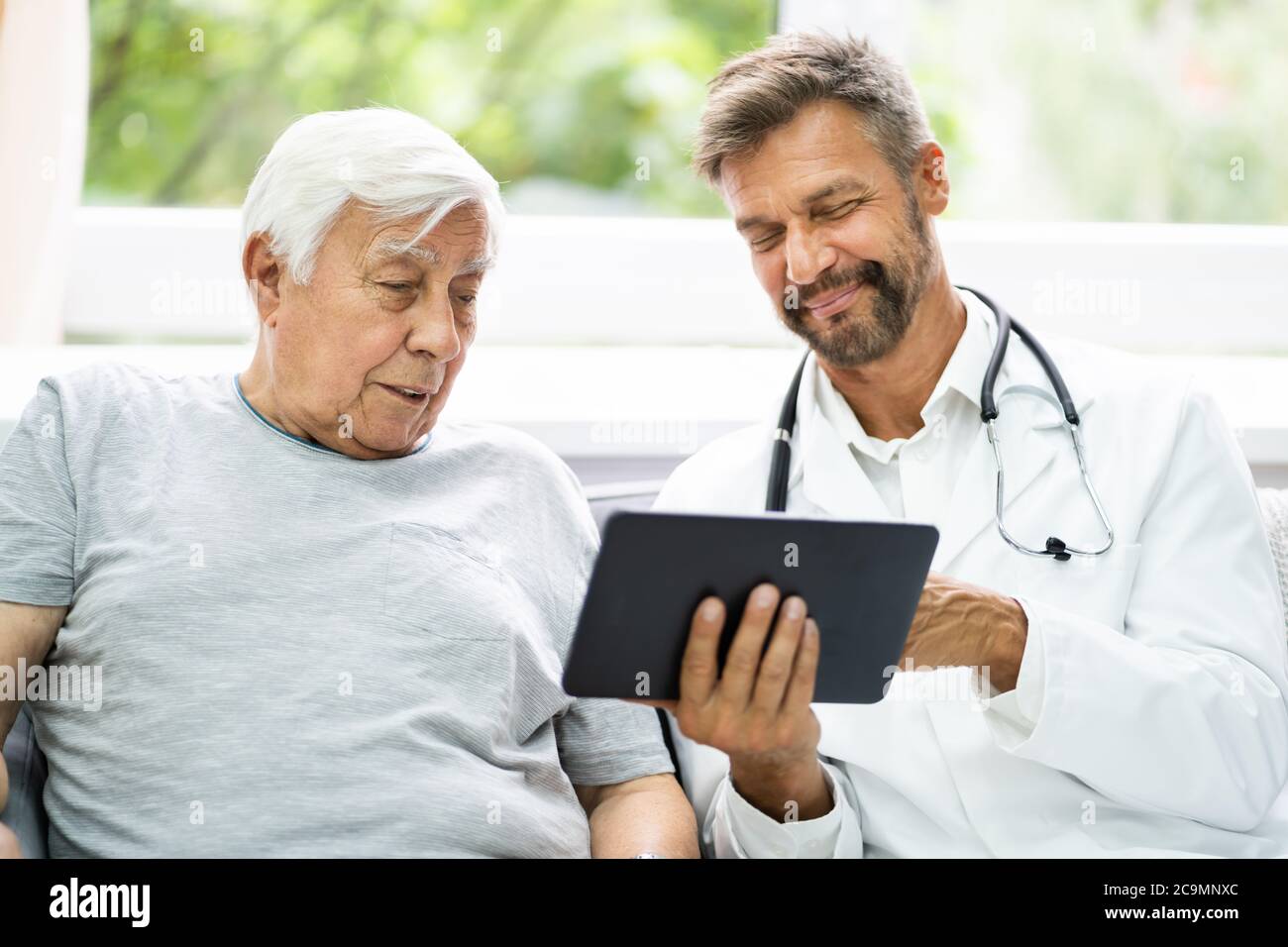 Home Care paciente anciano mirando imágenes XRay mostradas por su médico Foto de stock