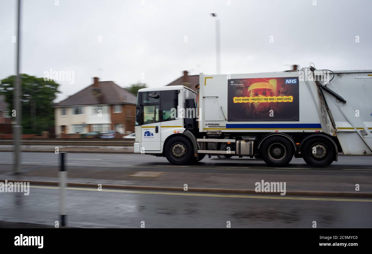 Un trabajador clave de la ciudad de Southampton camión de recogida de residuos que muestra una estancia Covid-19 en casa proteger el cartel de mensaje de información de NHS en el lado. Foto de stock