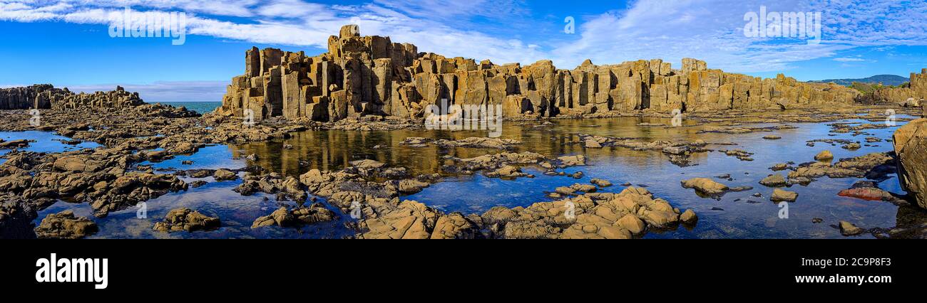 Panorama de formaciones de roca basáltica y reflexiones de piscinas rocosas en la cantera de Bombo Headland, costa de Nueva Gales del Sur, Australia Foto de stock