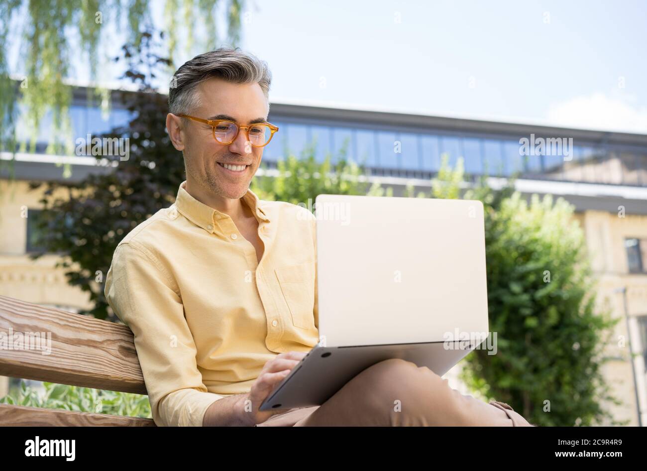 Freelancer copywriter usando computadora portátil, escribiendo en el teclado. Retrato de hombre maduro guapo teniendo videoconferencia Foto de stock