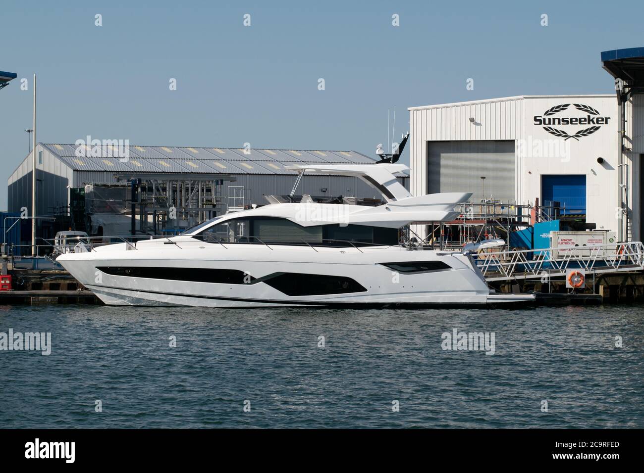 Astillero Sunseeker en Poole, Dorset Reino Unido con yate en el agua y logotipo en el edificio en el fondo Foto de stock