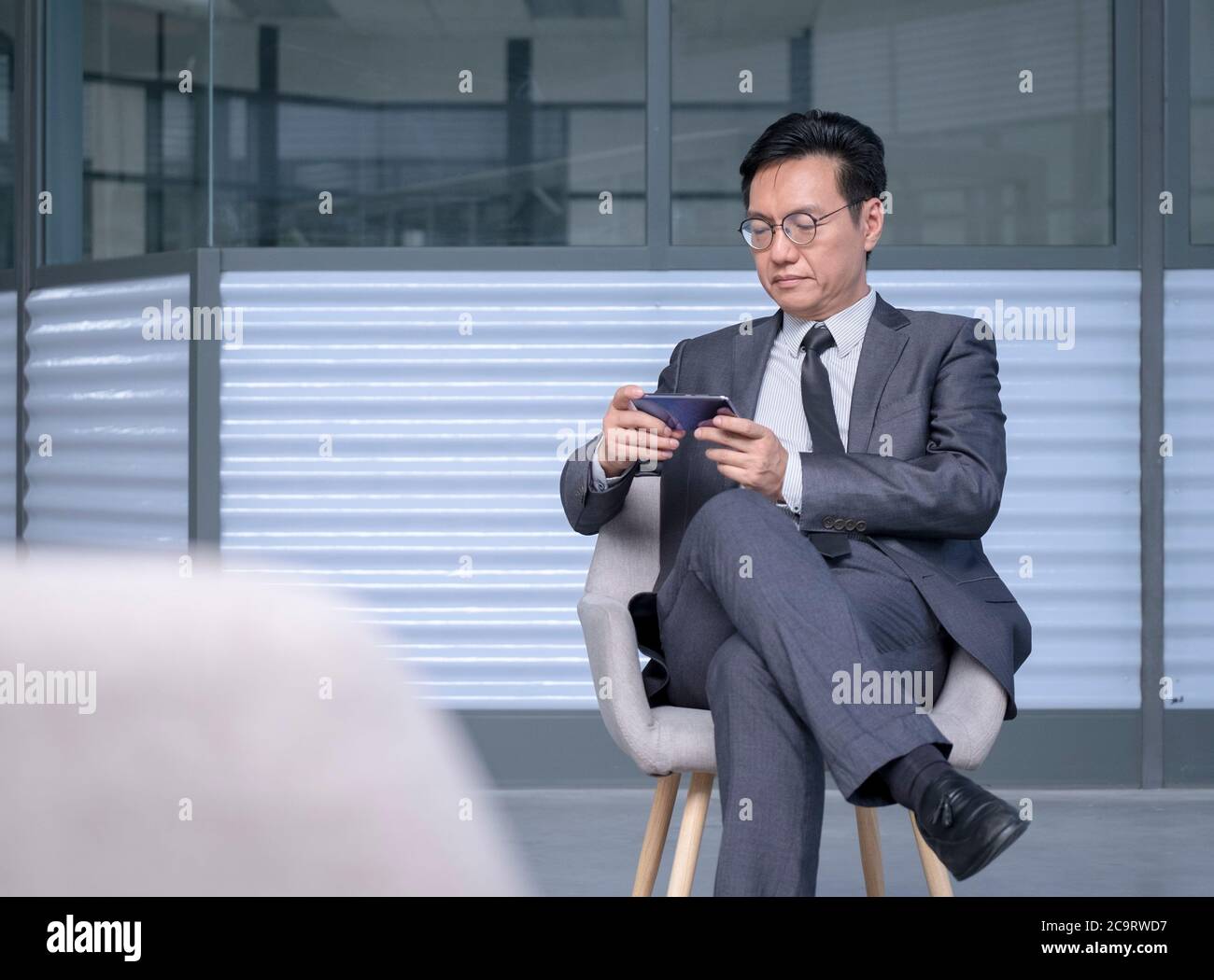 Hombre de negocios chino en traje y corbata utilizando el teléfono celular  para ver streaming en vivo o vídeo Fotografía de stock - Alamy