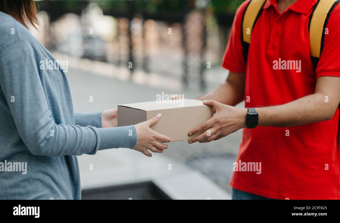 Compras en línea y entrega a domicilio. La mujer toma una caja del  mensajero con la mochila Fotografía de stock - Alamy