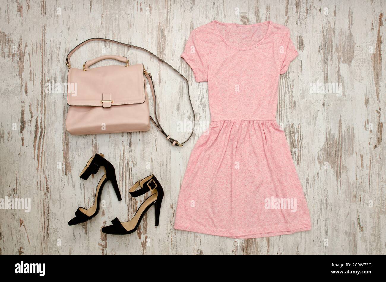 Vestido rosa zapatos negros y una bolsa beige. Concepto de moda