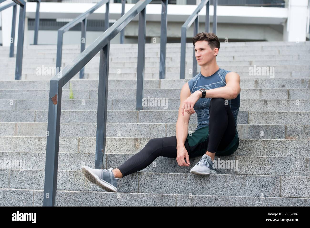 Retrato de un hombre confiado. Joven deportista sentado al aire libre después de un buen entrenamiento de jogging. Hombre joven en ropa Relájese después del entrenamiento. El chico se sienta