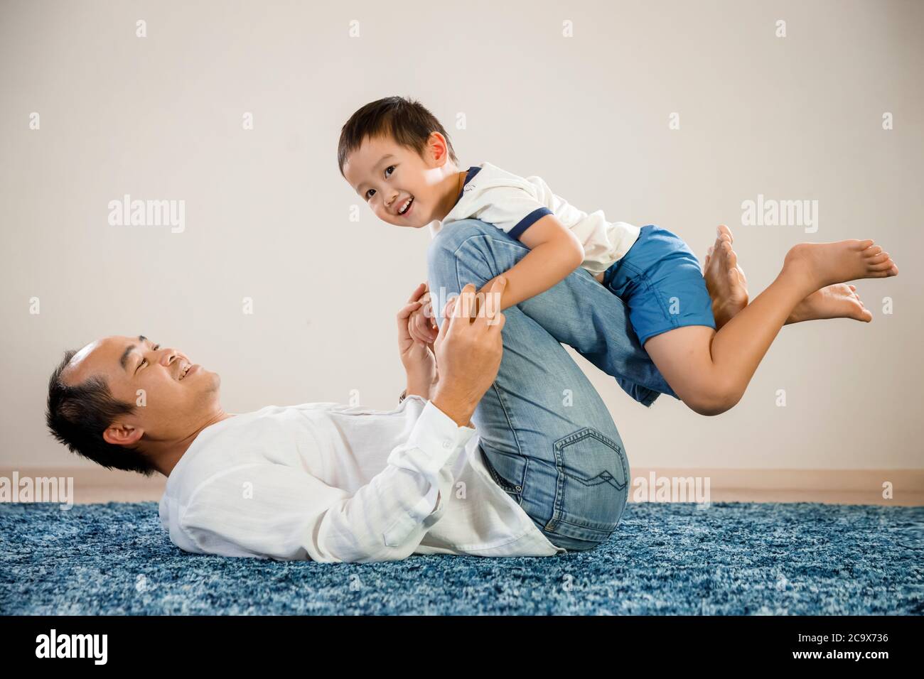 Retrato asiático del padre y el hijo, concepto del día del padre, hombre vietnamita feliz y sonriente sentado en el suelo con su hijo en brazos, orgulloso padre e hijo Foto de stock