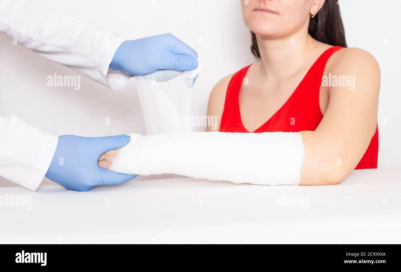 El cirujano médico establece un yeso y un vendaje apretado en la mano de una niña con una fractura de desplazamiento, fondo Foto de stock