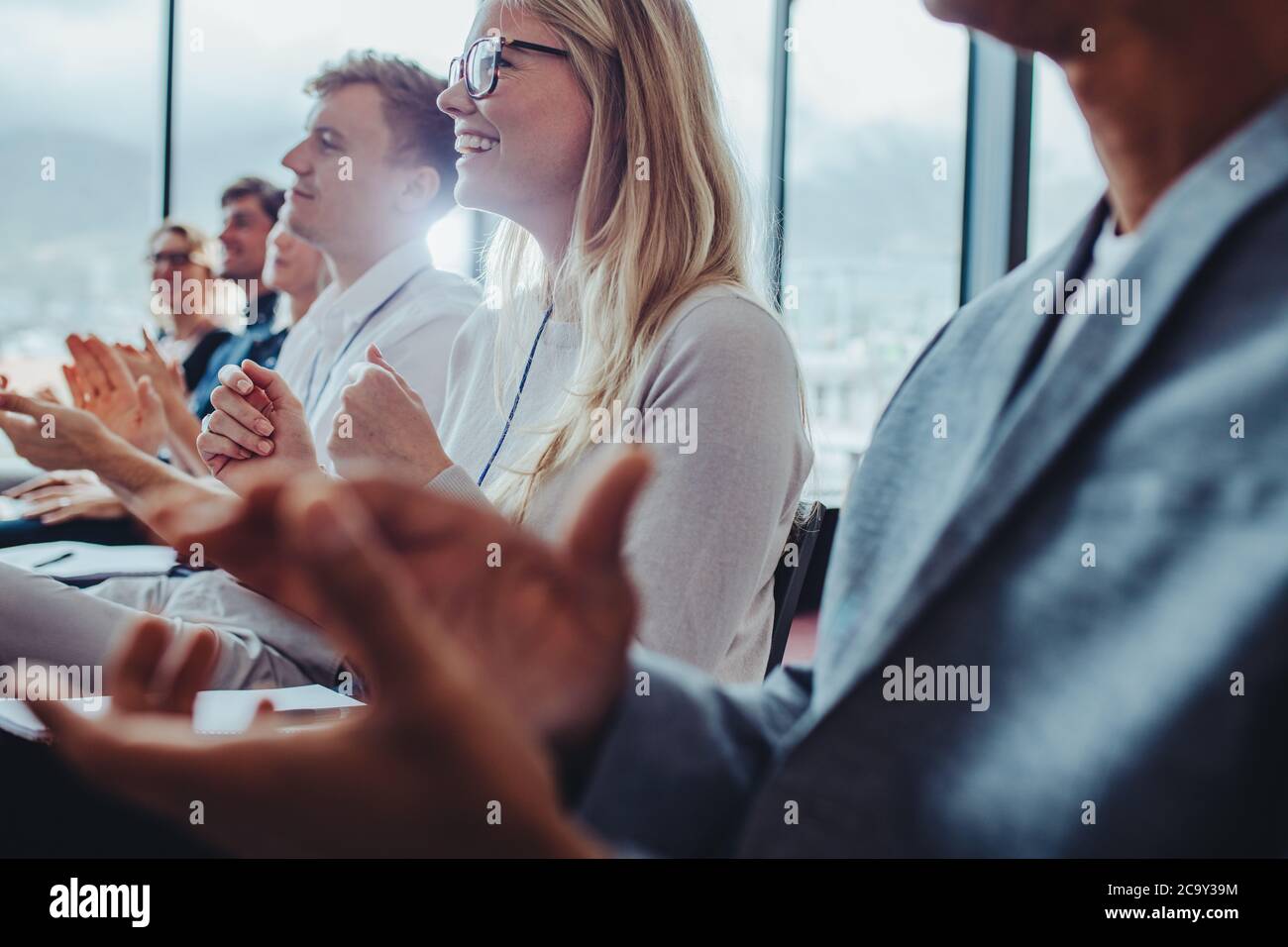 Los empresarios se aferran a las manos después de una conferencia exitosa. Grupo de hombres y mujeres aplaudiendo después de una reunión productiva. Foto de stock