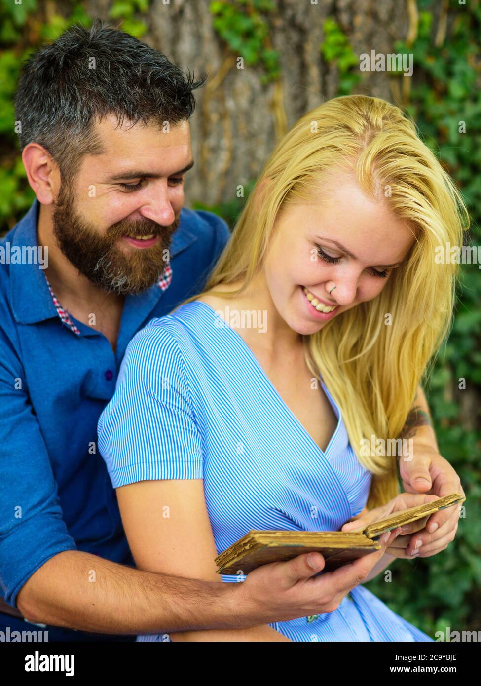 Fecha romántica y concepto de amor. Pareja en amor abraza al aire libre, fondo de la naturaleza, desenfocado. Chica con cara feliz escuchar hombre barbudo leyendo poemas. Pareja romántica tiene un libro Fecha romántica y concepto de amor. Pareja en amor abraza al aire libre, fondo de la naturaleza, desenfocado. Chica con cara feliz escuchar hombre barbudo leyendo poemas. Pareja romántica tiene un libro