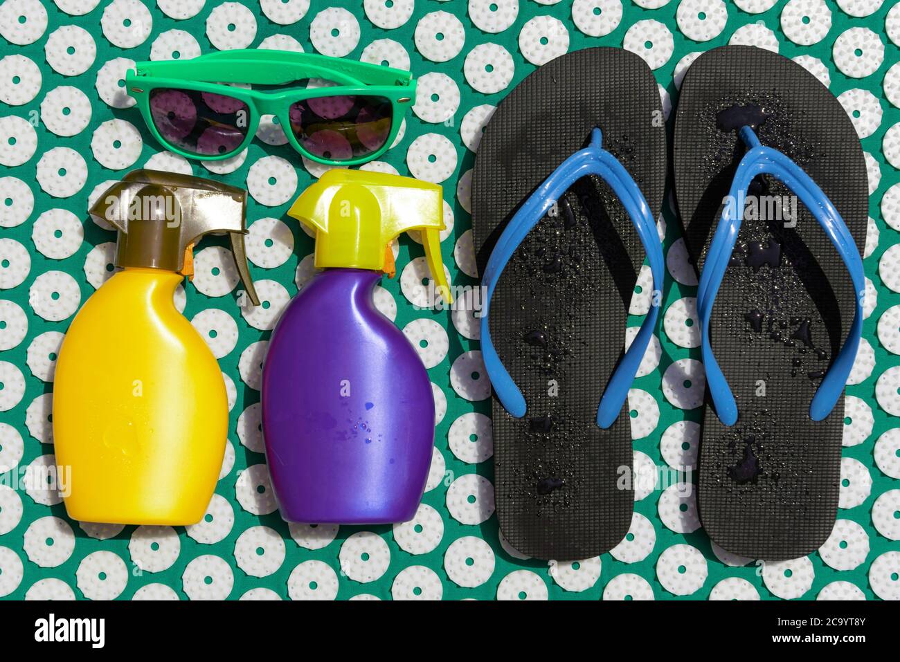 Colchoneta de acupresión de masaje con coloridos artículos de playa.  Chanclas, protector solar y gafas de sol Fotografía de stock - Alamy