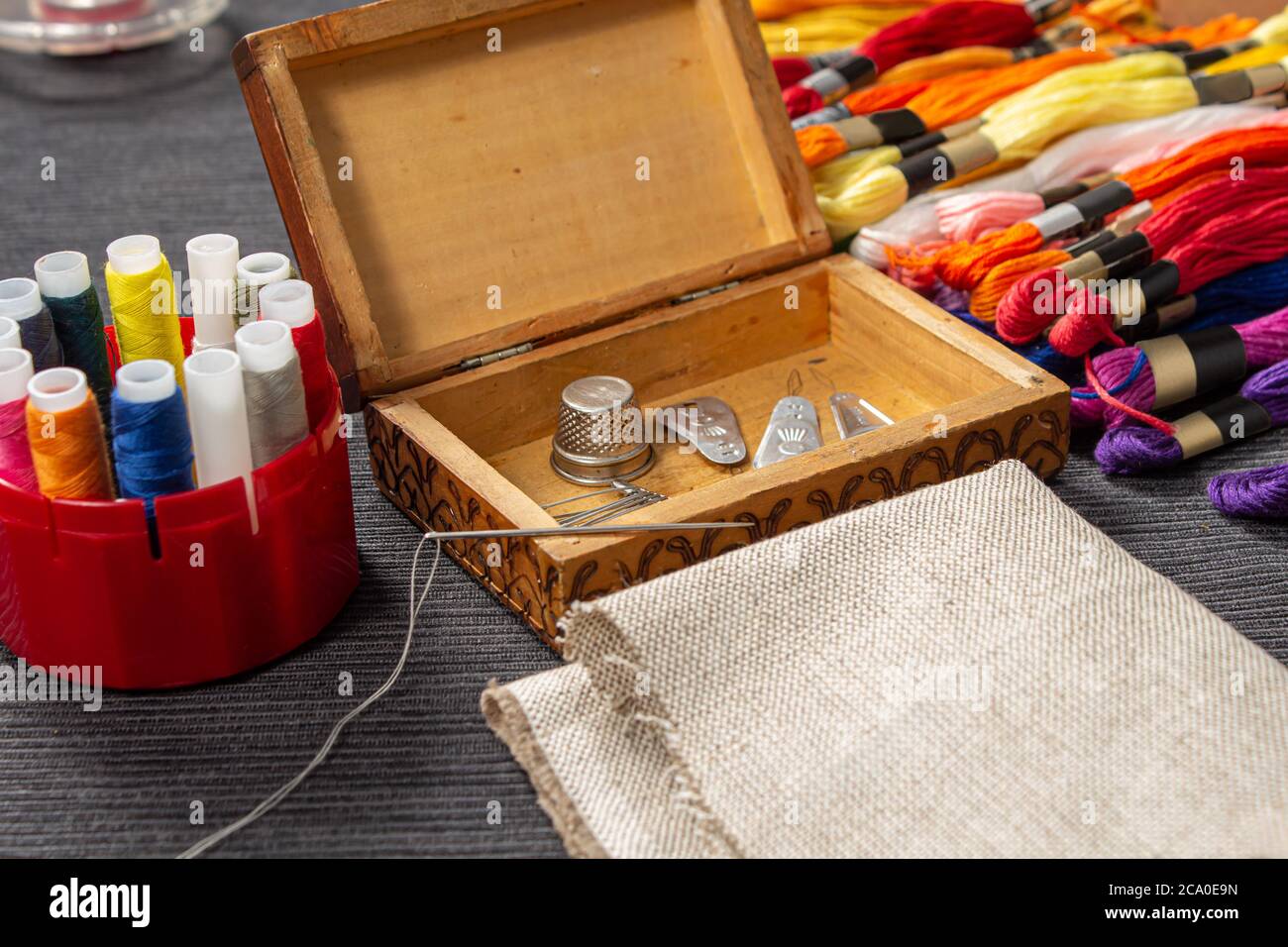 Los accesorios de costura están en una caja de madera. El mulina y los hilos coloreados se encuentran en la mesa al lado del ataúd. La aguja con el roscado se encuentra Foto de stock