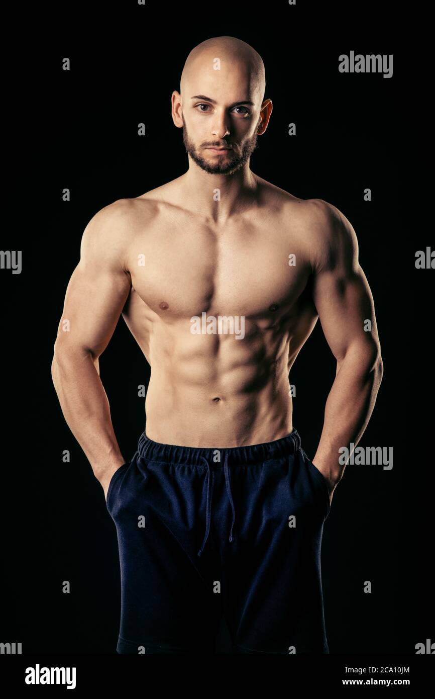 Hombre atlético con las manos en el bolsillo mira directamente a la cámara  mientras que muestra su abs bien entrenado Fotografía de stock - Alamy