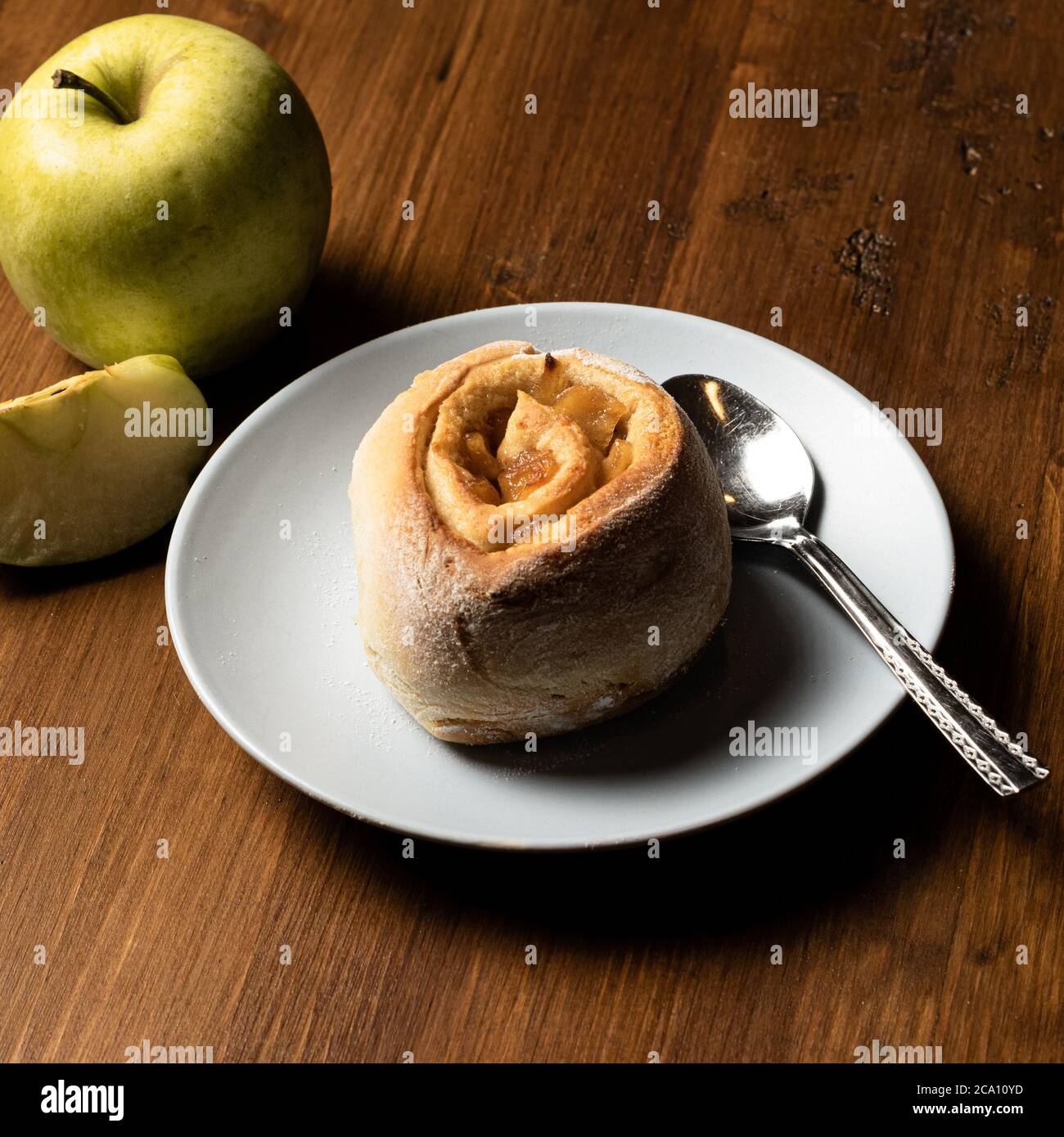 Rollo de canela vegetariana hecho con manzana sobre una tabla de madera. Foto de stock