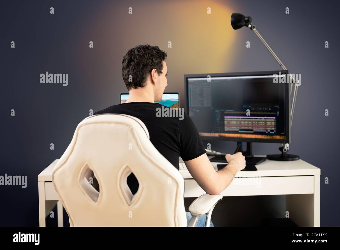 editor de vídeo independiente sentarse en silla blanca y escritorio en su  oficina y cortar algunas secuencias de vídeo con la tableta gráfica  Fotografía de stock - Alamy