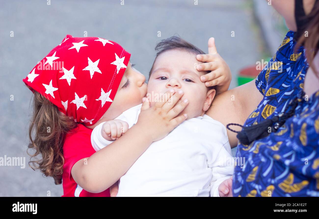 el niño en el parque está besando a su recién nacido hermano Foto de stock