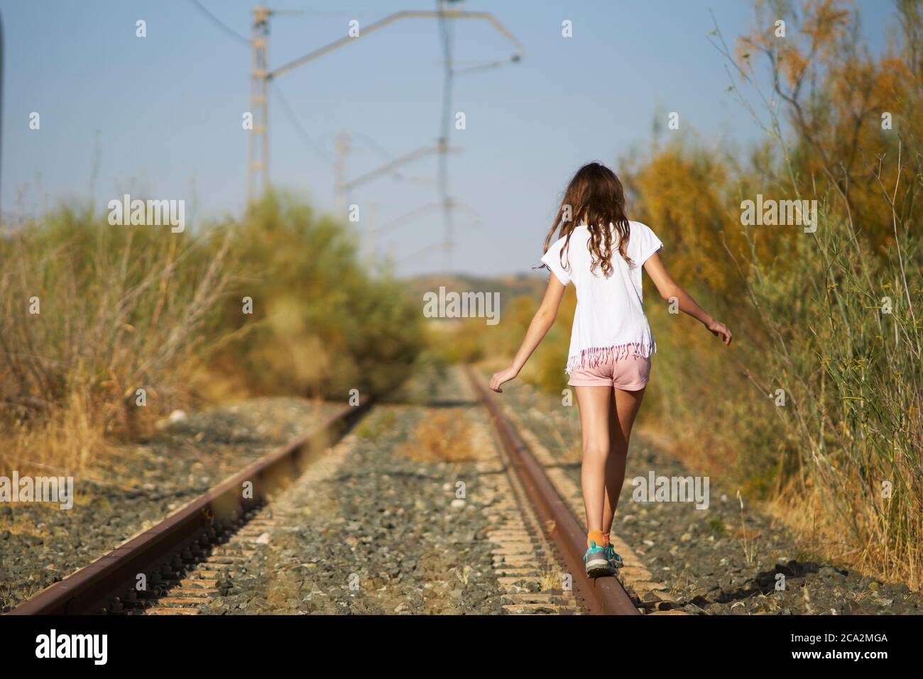 chica jugando equilibrio en una pista de tren abandonada en el campo Foto de stock