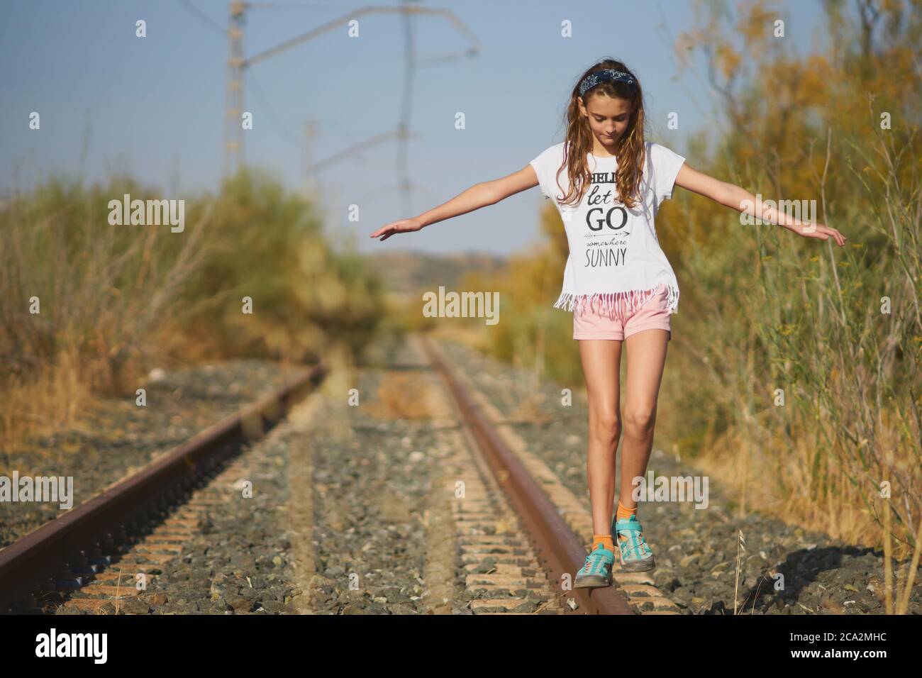 chica jugando equilibrio en una pista de tren abandonada en el campo Foto de stock