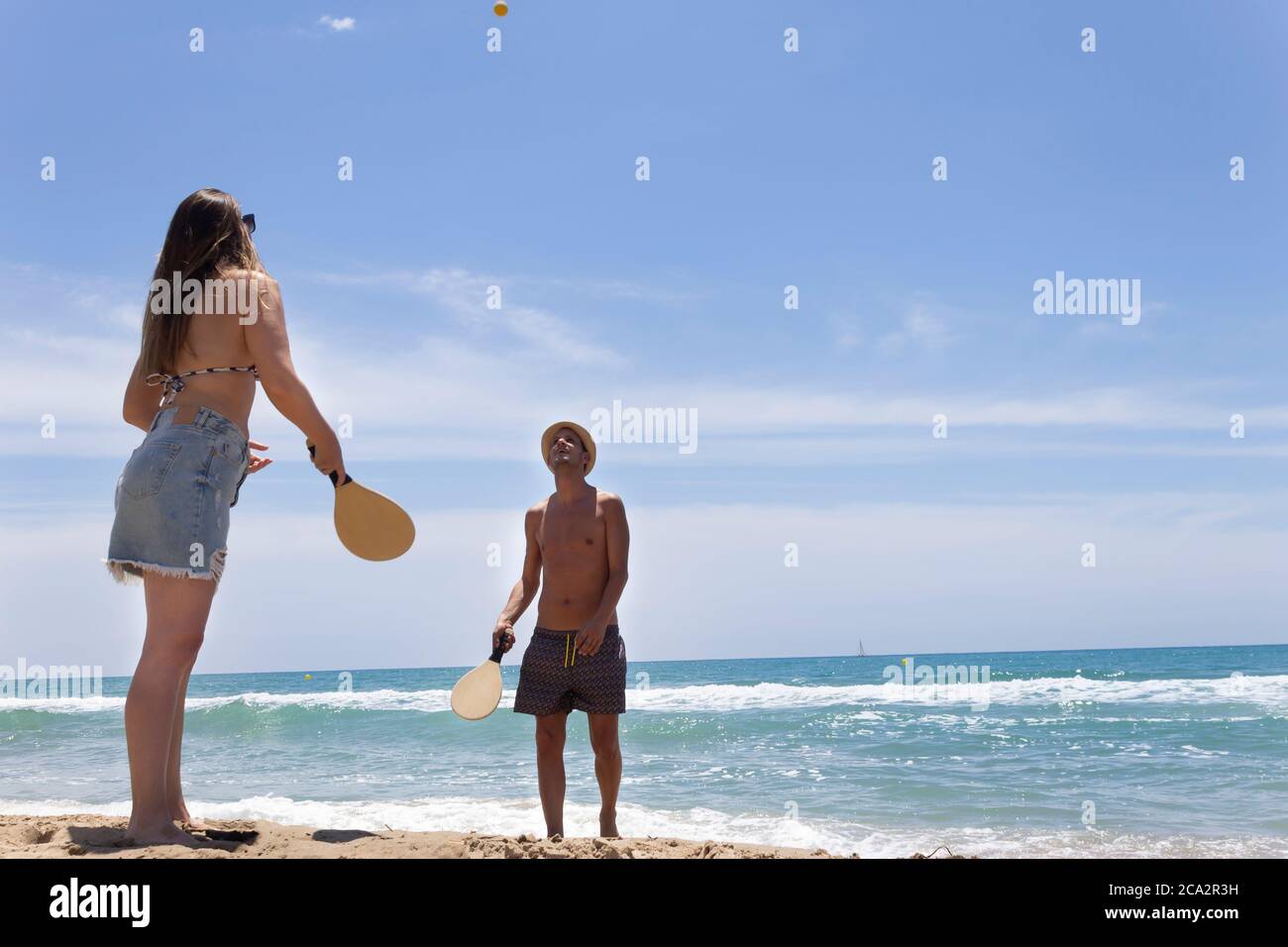 Joven hermosa pareja jugando paddle ball en la playa en verano (tenis).Happy Holidays concepto estilo de vida. Foto de stock