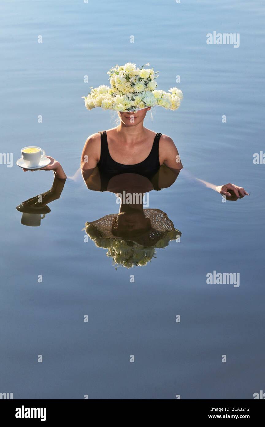 Mujer joven con sombrero de flores sirviendo una taza de café. Foto de stock