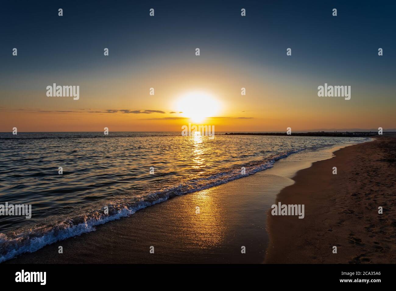 Una maravillosa puesta de sol en el horizonte en la playa. El final del día en el mar. Colores brillantes e intensos de la naturaleza. Foto de stock