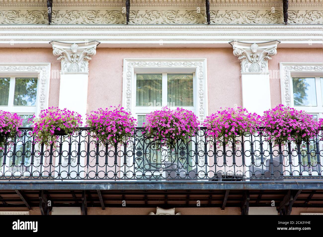 balcón con baranda de hierro forjado con macetas colgantes para flores con  petunias en flor en la fachada del edificio con det arquitectónico  Fotografía de stock - Alamy