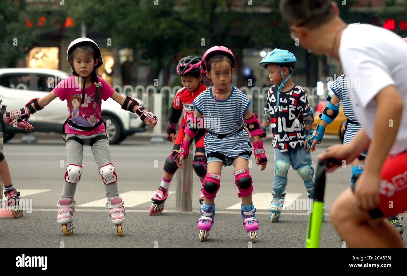 Pekín, China. 04 de agosto de 2020. A las jóvenes chinas, que no llevan máscaras protectoras, se les enseña lo básico de una nueva moda deportiva - patinaje en línea - fuera de un parque, ya que la vida vuelve a la normalidad después del susto Covid-19 en Beijing el martes, 4 de agosto de 2020. China y la Organización Mundial de la Salud (OMS) están discutiendo planes para rastrear el origen del brote de coronavirus en Wuhan tras una visita al país de dos expertos de la agencia de las Naciones Unidas (ONU), informó el Ministerio de Asuntos Exteriores el martes. Foto de Stephen Shaver/UPI crédito: UPI/Alamy Live News Foto de stock