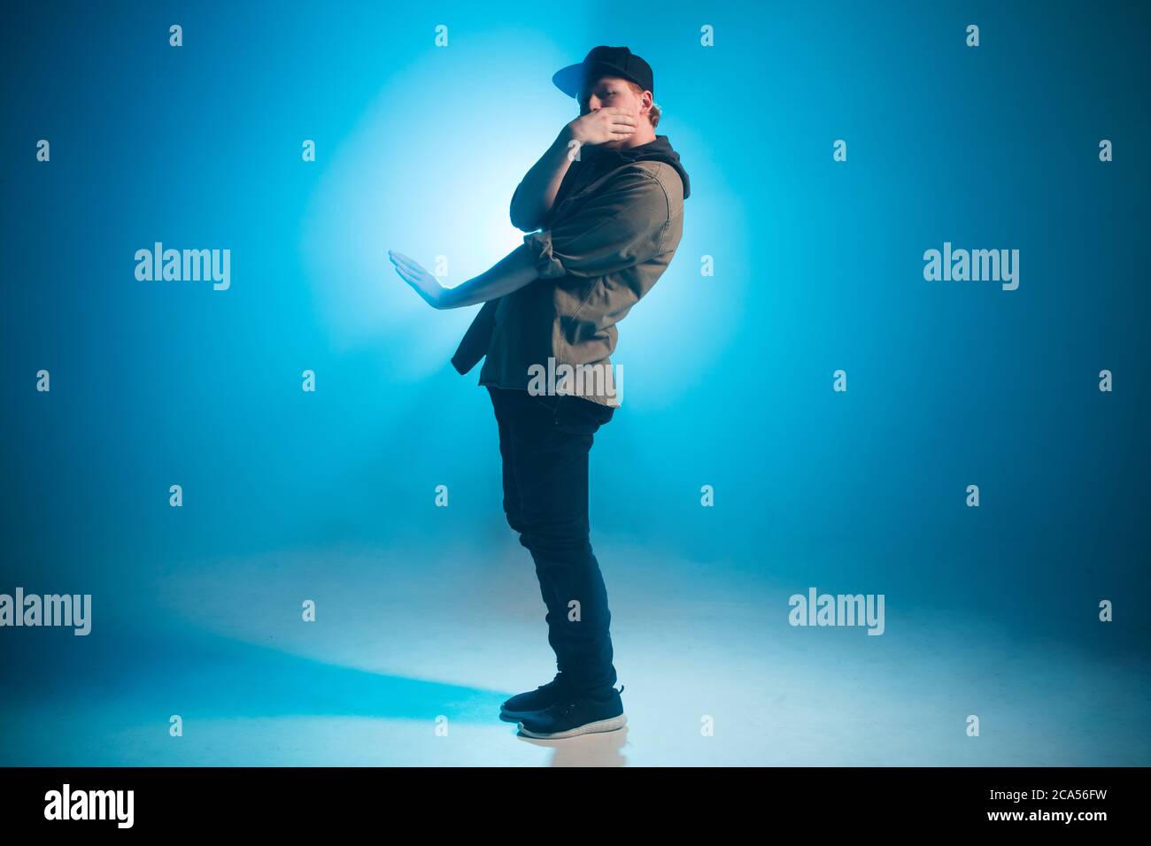 Bailarín de hip-hop de estilo deportivo y moderno vestido con ropa urbana  muestra su baile sobre fondo azul de estudio Fotografía de stock - Alamy