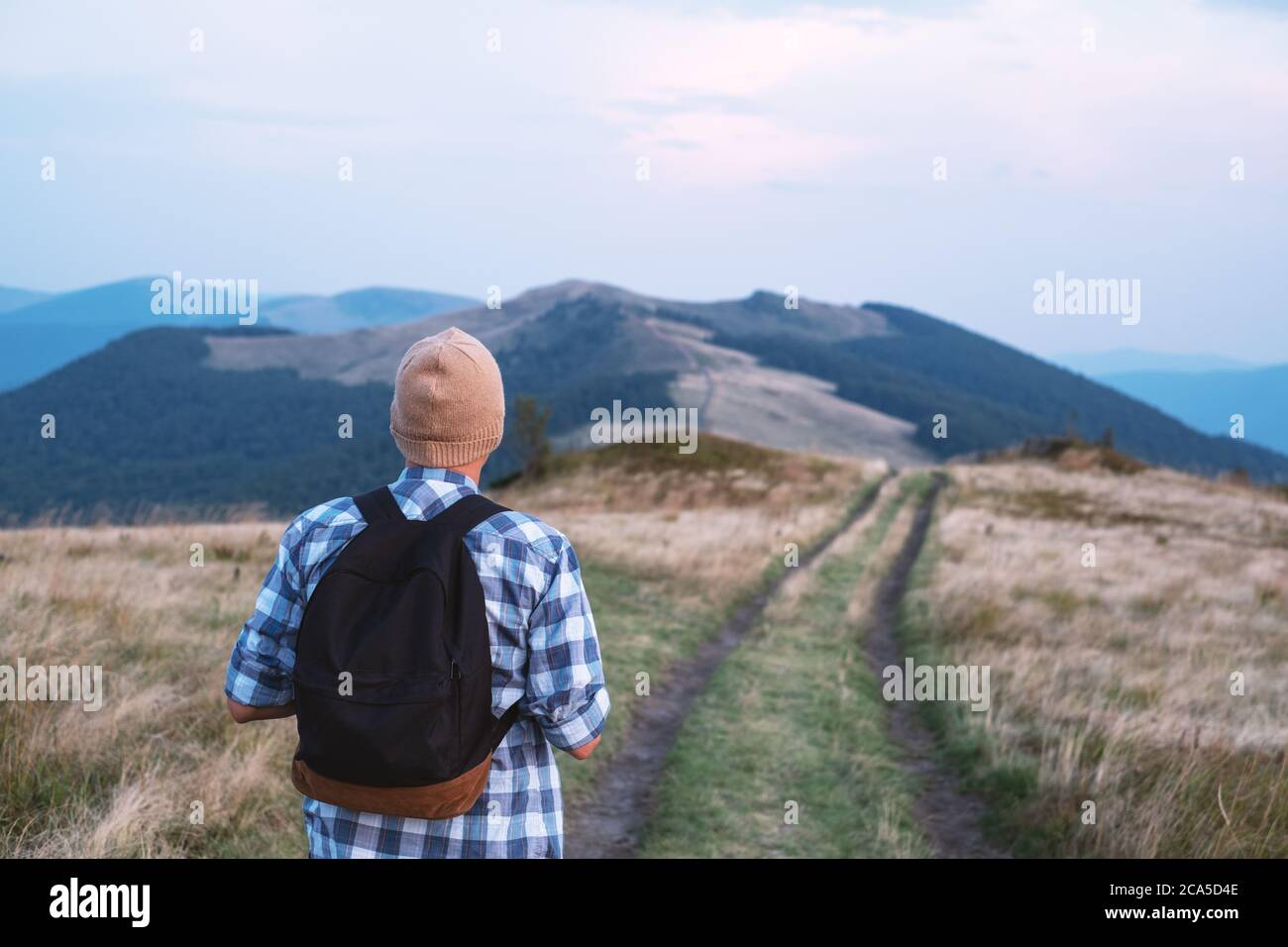 Hombre con mochila en montañas road. Concepto de viaje. Fotografía paisajística Foto de stock