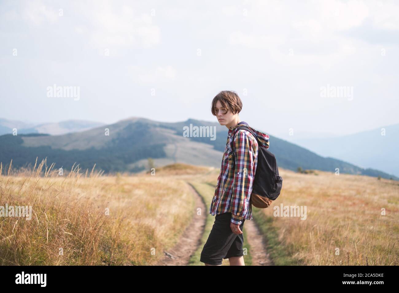 Niño con mochila en carretera de montaña. Concepto de viaje. Fotografía de paisajes Foto de stock