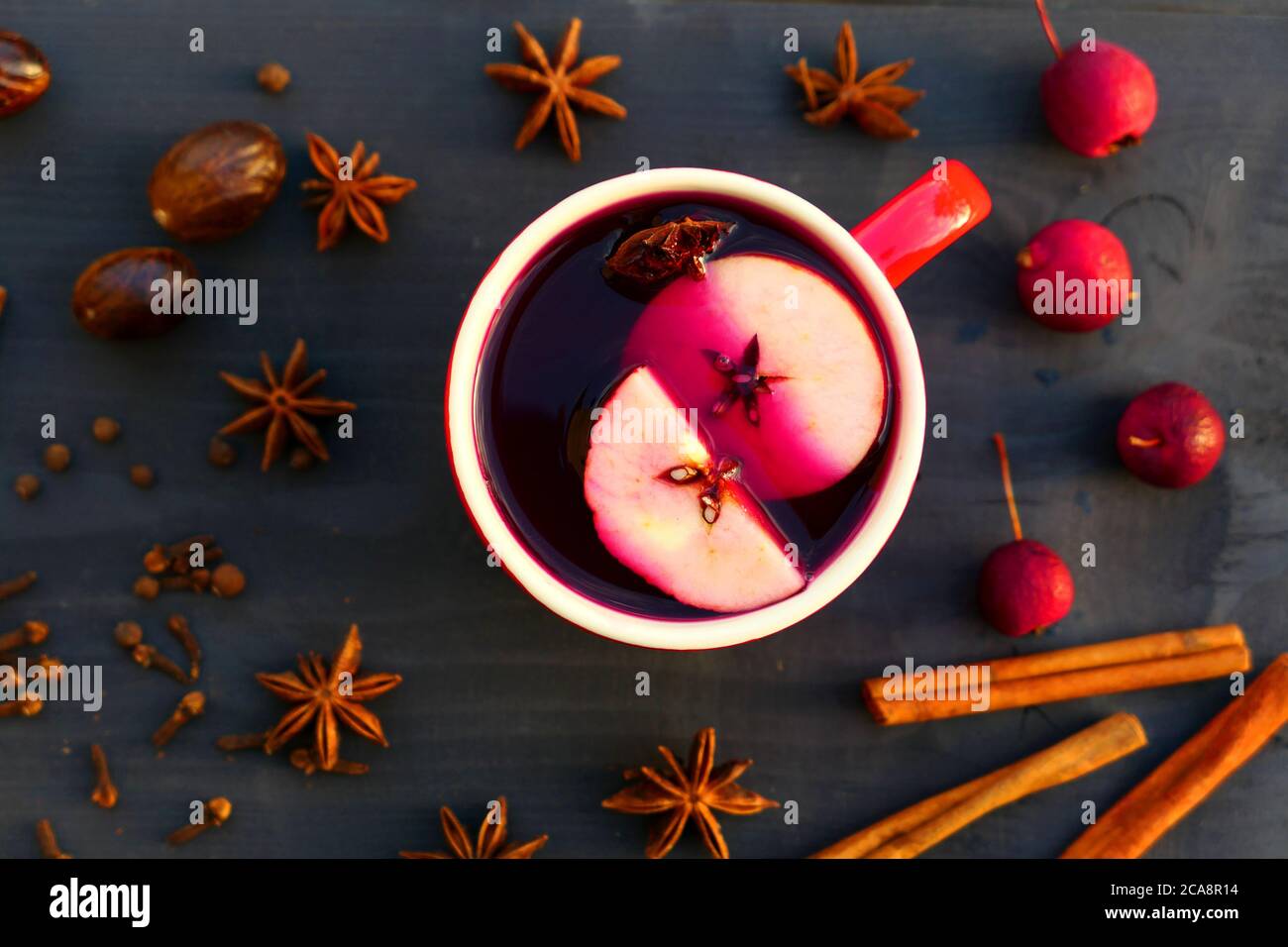 Vino de Navidad con especias y manzana en taza roja sobre fondo de