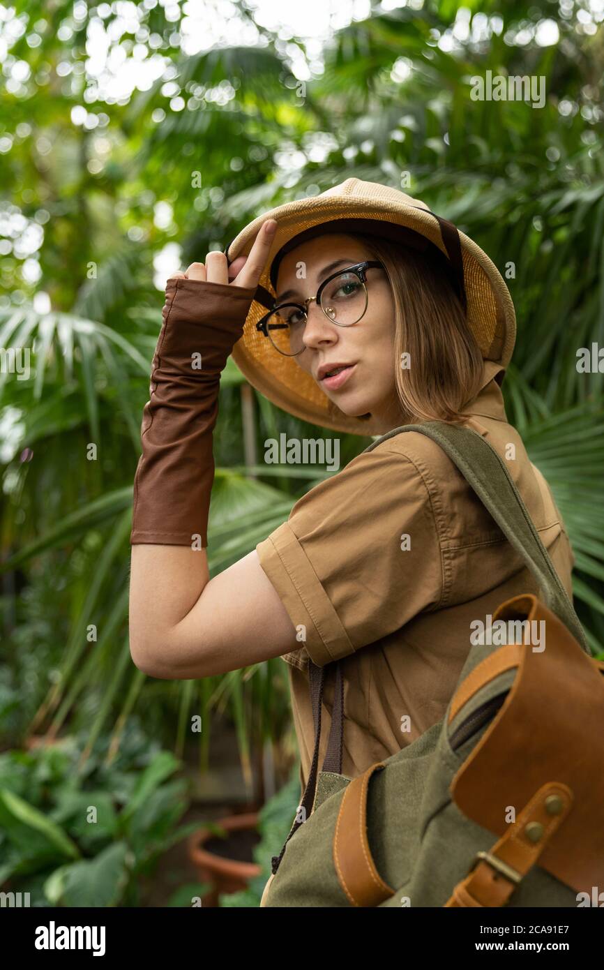 Mujer botánica vestida en estilo safari en invernadero. Naturalista en ropa  khaki, guantes de castor con mochila paseos en la selva tropical rodeada  por p Fotografía de stock - Alamy