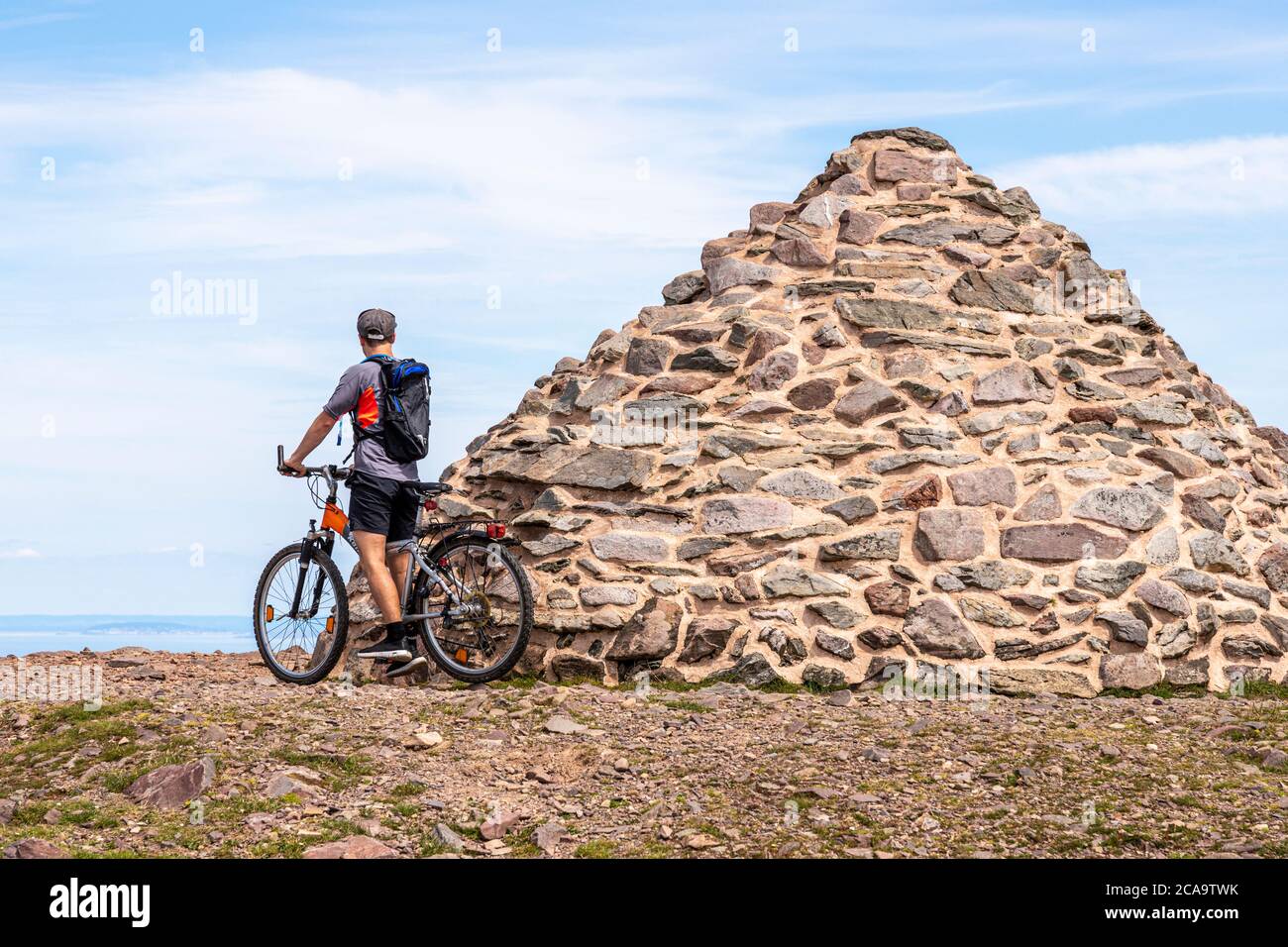 Parque Nacional Exmoor - un ciclista de montaña disfrutando de la vista desde el cairn marcando el punto más alto de Exmoor, Dunkery Beacon 1705 pies 520 metros, Som Foto de stock