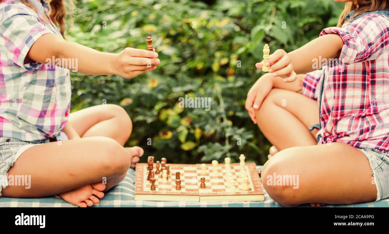 Jugar al ajedrez. Hermanas jugando al ajedrez. Los niños juegan al ajedrez al aire libre la naturaleza de fondo. Concepto de deporte y pasatiempo. El concepto de estrategia. El desarrollo cognitivo. Juego intelectual. La toma de decisiones. Los niños inteligentes. Foto de stock