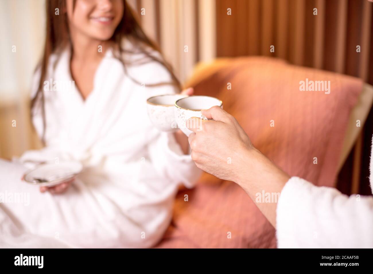 una pareja joven que se alaba de un ambiente de miel en la habitación del hotel. foto de primer plano vista lateral. café matutino para gente amante Foto de stock