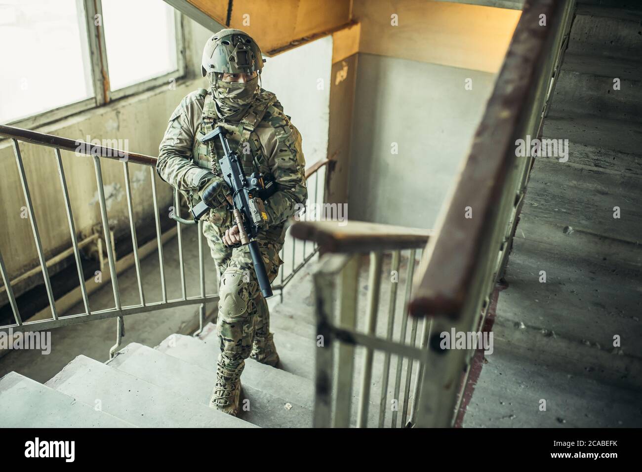 el concepto del ejército. soldado con arma en el aterrizaje, subiendo las escaleras, buscando enemigo para disparar, proteger. Foto de stock
