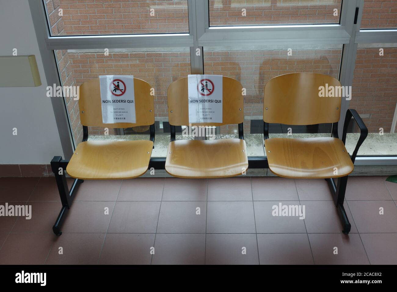 Sillas en una sala de espera de un hospital en Italia con el mensaje "prohibición de sentarse" para el distanciamiento social establecido para la emergencia Covid19 Foto de stock