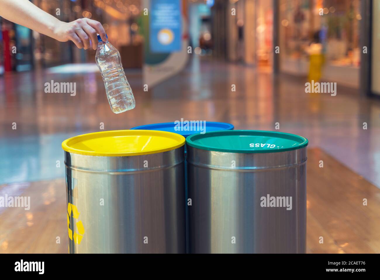Mujer poniendo una botella de plástico vacía en un contenedor de reciclaje  en el centro comercial. Puede de basura diferente con bolsas de basura de  colores Fotografía de stock - Alamy